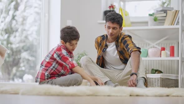 Wide Shot Portrait of Friendly Middle Eastern Brothers Sharing Secrets and Problems Sitting at Home alt
