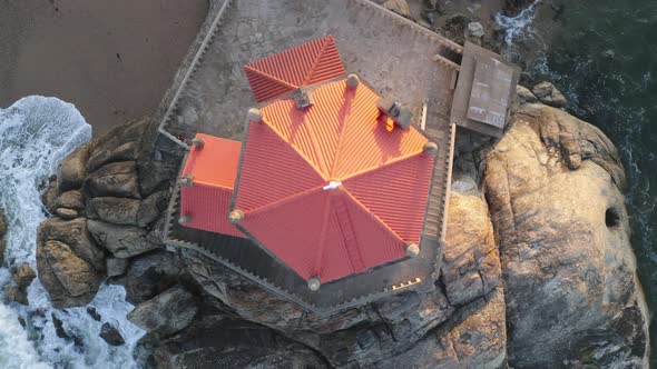 Capela Senhor da Pedra most beautiful chapel drone aerial top view from above on a beach with waves alt