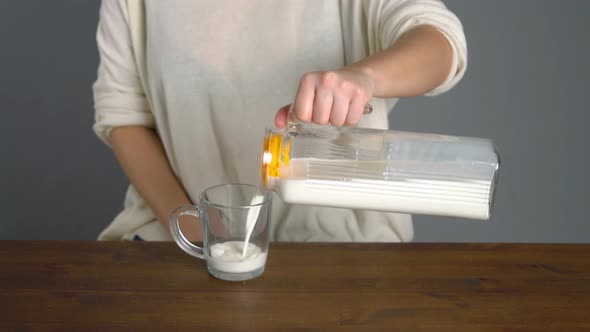 Female Pouring Jug of Milk Into a Glass and Drinking