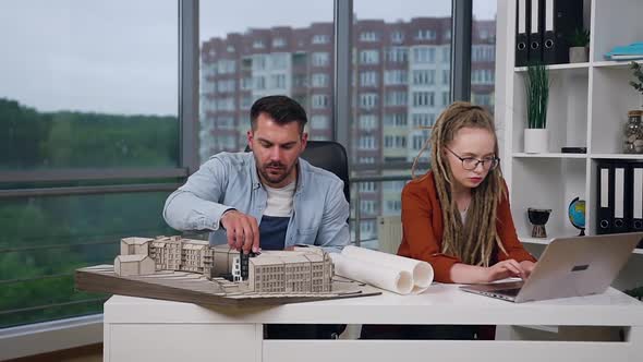 Male and Female Colleagues which Working Together with Model of New Buildings alt