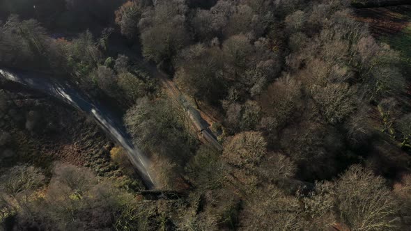 Aerial view of a steam train leaving a little town station in Wales and trave