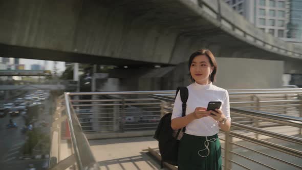 Portrait of asian woman with earphone listening music and using smartphone