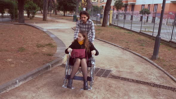 disabled person - man pushes his girlfriend with paraplegia in a garden alt