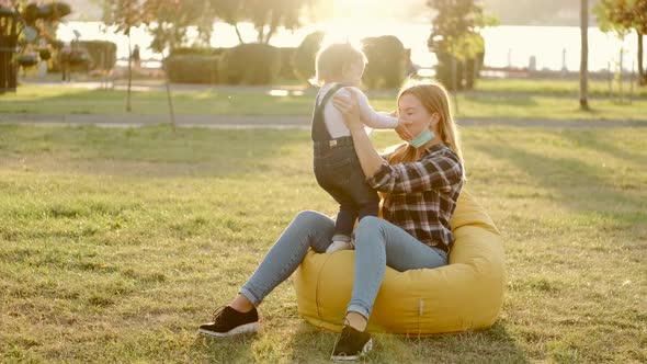 Mother and Little Daughter Are Having Fun in the Park in Sunny Weather alt