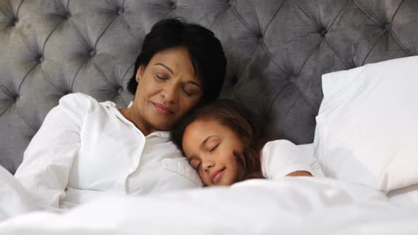 Grandmother and granddaughter sleeping together in bedroom 4k alt