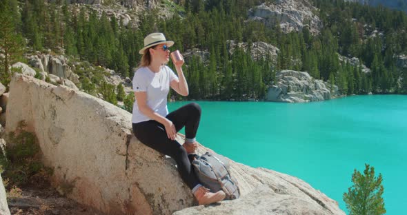 Slow Motion Happy Traveler Woman Sitting on the Rock with Scenic Blue Lake View alt