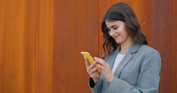 Side View of Millennial Happy Girl Scrolling Phone Screen While Checking Content and Smiling. Young alt