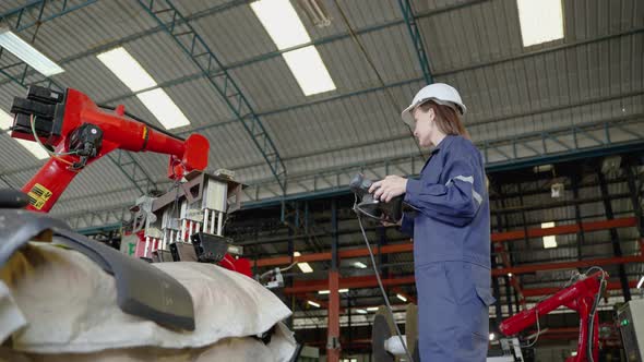female engineer operating a mechanical arm, she is inspecting and testing the operation