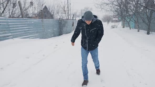 Man Walking Through Snowy Weather and Slips alt