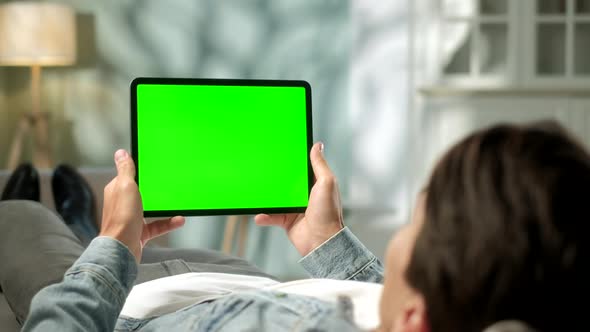 View From the Shoulder of Man Using Hand Gestures on Green Mock-up Screen Digital Tablet Computer in alt