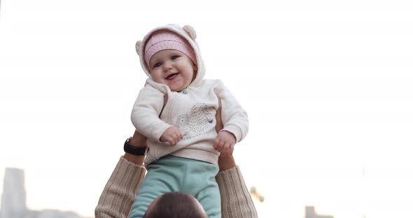 Adorable Baby Girl in Pink in Somebody's Hands Up in High