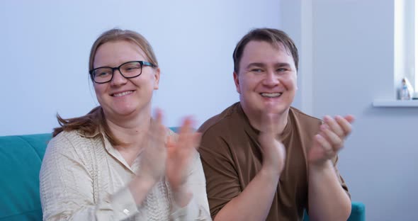 Smiling Man and Woman Clap Their Hands and Gesture Encouragement to Someone