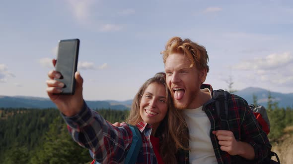 Positive Woman and Man Taking Selfie on Smartphone During Hike in Mountains alt