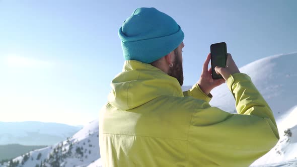 Hipster Taking Photos of Mountains With His Smartphone