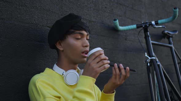 Transgender adult drinking coffee in the street alt