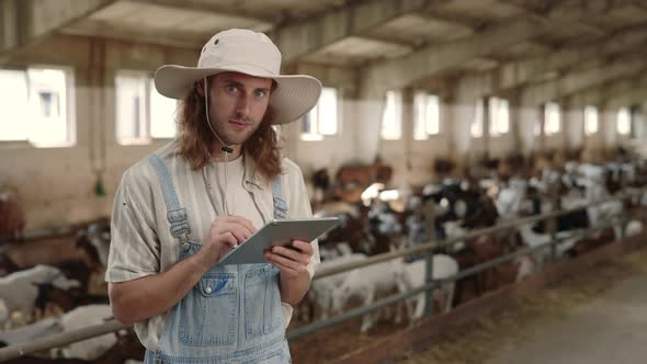Agronomist Using Digital Tablet While Standing at Goat Farm alt