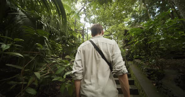 Following Dolly Shot of a Young Man Walking Up the Stairs Towards a Stone Pillars of an Ancient alt