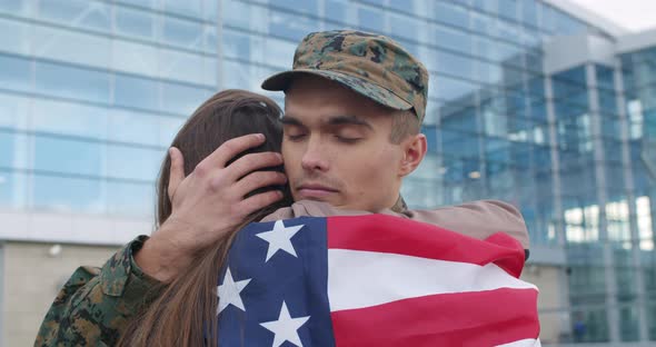 Soldier Hugging Girl Covered with American Flag. alt