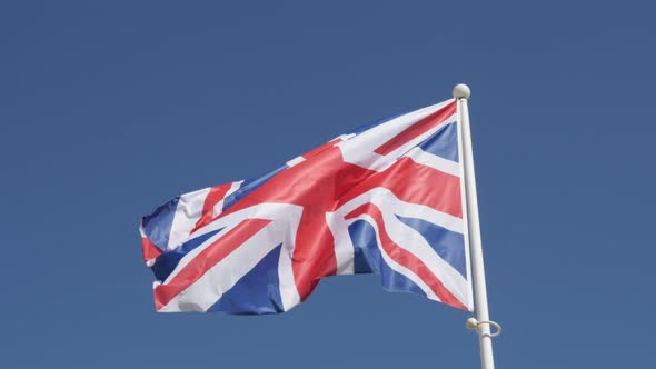 Union Jack national Great Britain symbol waving on flag-pole against blue sky 4K 2160p 30fps UHD foo