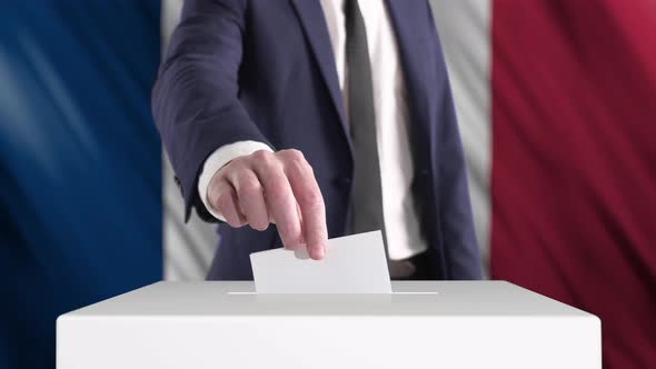 Voting. Man Putting a Ballot into a Voting Box with French Flag on Background.