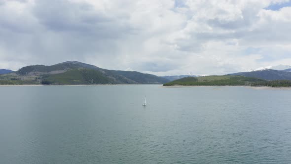 Aerial Flyby Shot of a Lone Sailboat on a Beautiful Mountain Lake in Colorado (Dillon Reservoir) alt