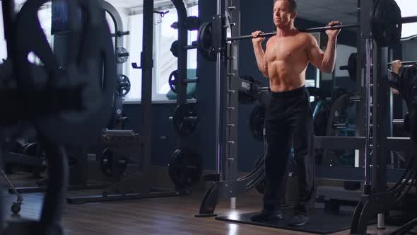 Senior Fit Man Bodybuilder Doing Barbell Squats at Gym