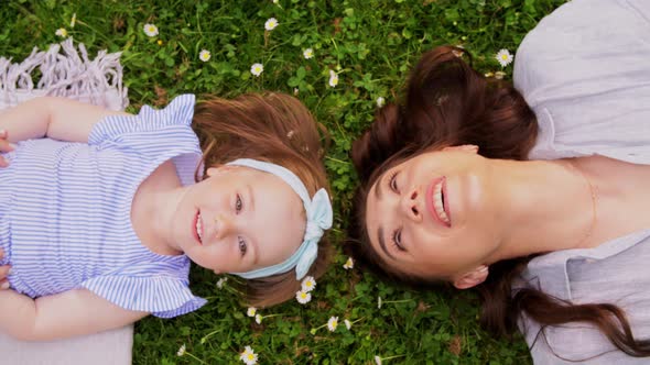 Happy Mother with Baby Girl Lying on Grass in Park