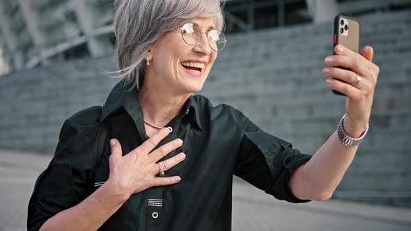 Closeup Portrait of Confident and Attractive Grayhaired Woman Has a Video Call During Lunchtime alt