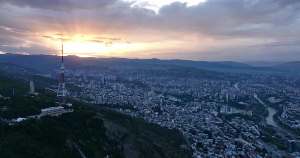 Aerial view of center of Tbilisi under Mtatsminda mountain at sunset. Georgia 2022 summer alt