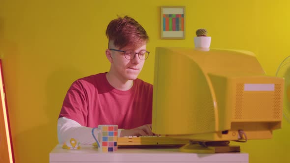 Young IT Specialist Is Working at Yellow Retro Computer