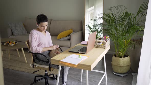 Woman Working on Laptop and Petting Cat at Home