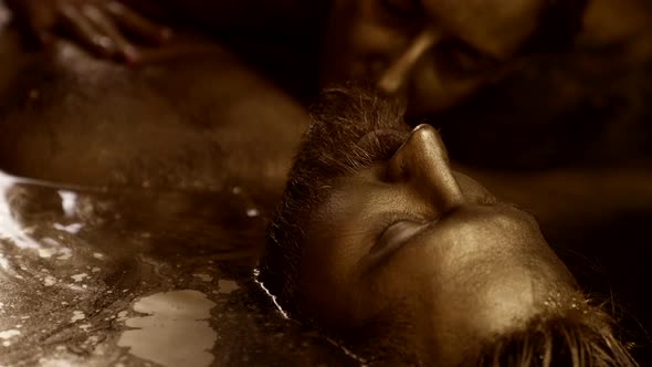 Sensual Woman is Seducing Emotionless Man Back to Life Lovers Covered By Golden Paint in Water alt