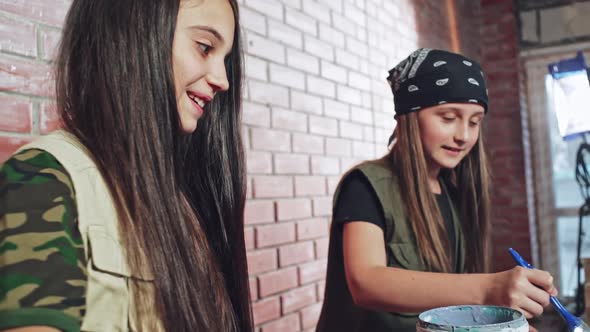 Two Teenagers Using Blue Paint to Decorate an Item alt