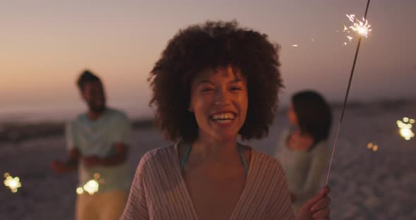 Mixed race woman playing with fire on the beach alt