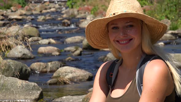 A Young Beautiful Woman Sits on the Ground in a Forest and Smiles at the Camera - Closeup alt