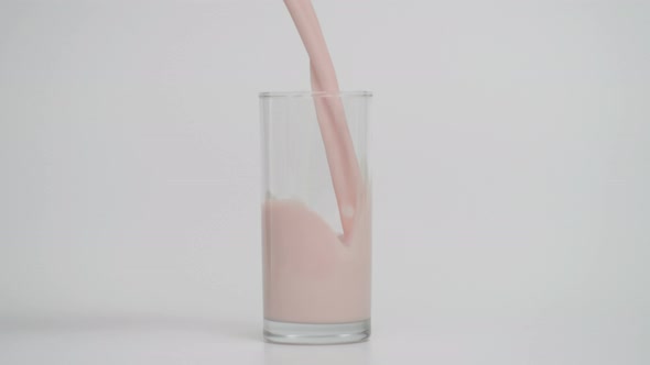 Slow Motion of Pouring Milk in Transparent Glass White Background alt