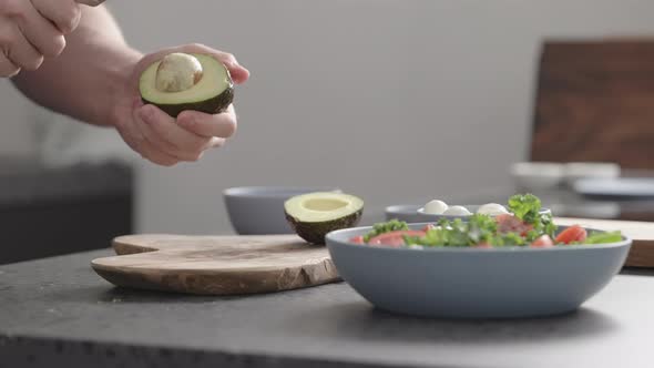 Slow Motion Man Make Salad with Kale Mozzarella Avocado and Cherry Tomatoes Remove Seed From Avocado