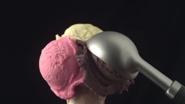 A disher scoop places a cacao ice cream ball onto a cornette