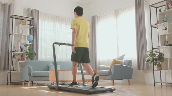 Back View Of Asian Man Training On Walking Treadmill At Home alt