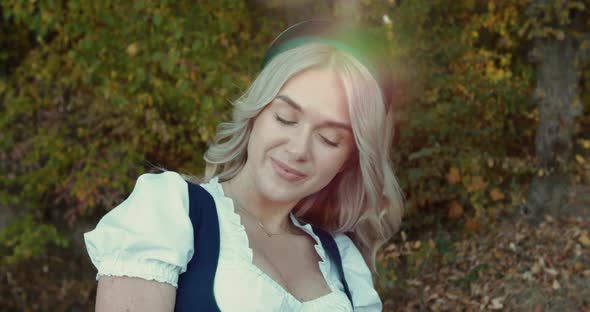 Pretty Blonde in Thematic Costume Flirts with Smile at Camera on Autumn Nature alt