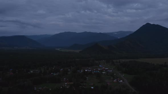 Aerial of valley in Altai and country houses under sunset sky
