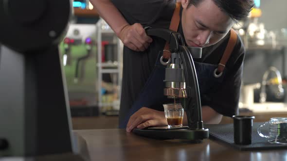 4K Asian man barista making hot espresso shot from flair espresso coffee maker alt