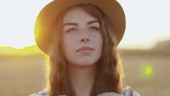 Girl with Freckles Touches Her Long Hair and Looks Aside Thoughtfully in Field alt