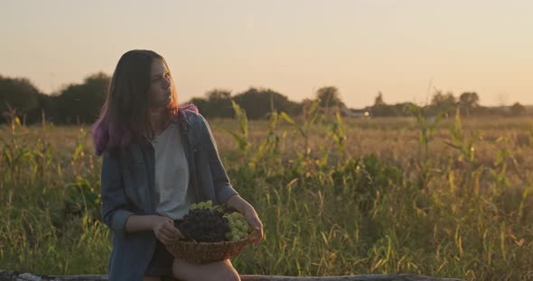 Young Girl Holding Basket of Grapes and Eating Grapes alt