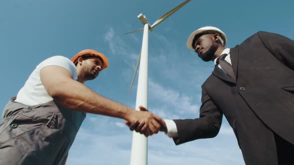 African American Inspector in Helmet and Black Suit Shaking Hands with Indian alt
