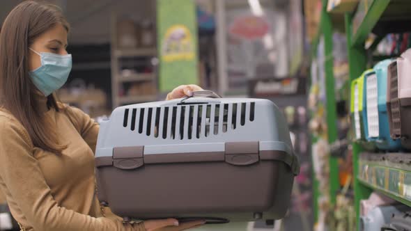 Young Woman Holds Blue and Brown Cat Carrier in Animal Shop alt