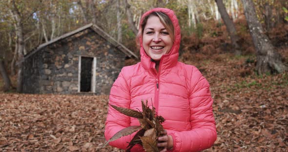 Happy young woman throwing leaves in the forest in autmn season alt