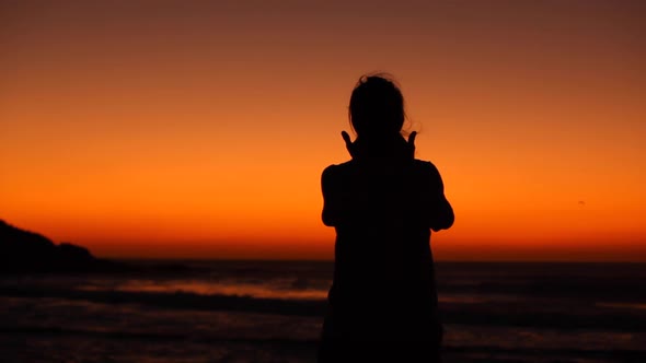 Silhouette view of a woman celebrating success at seaside at sunset in Fuerte