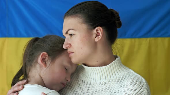 Young Woman with Her Daughter on the Background of the Flag of Ukraine