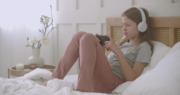 Little Girl Music Lover Is Listening Favorite Song By Smartphone and Headphone in Her Bedroom in alt